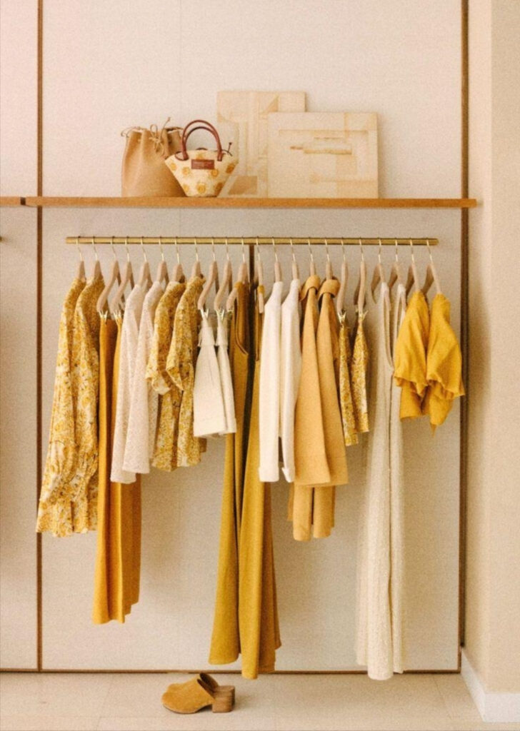 Οργανωμένη παρουσίαση ρούχων σε κρεμάστρα με λευκές και κίτρινες αποχρώσεις για καθαρό και αρμονικό visual merchandising.