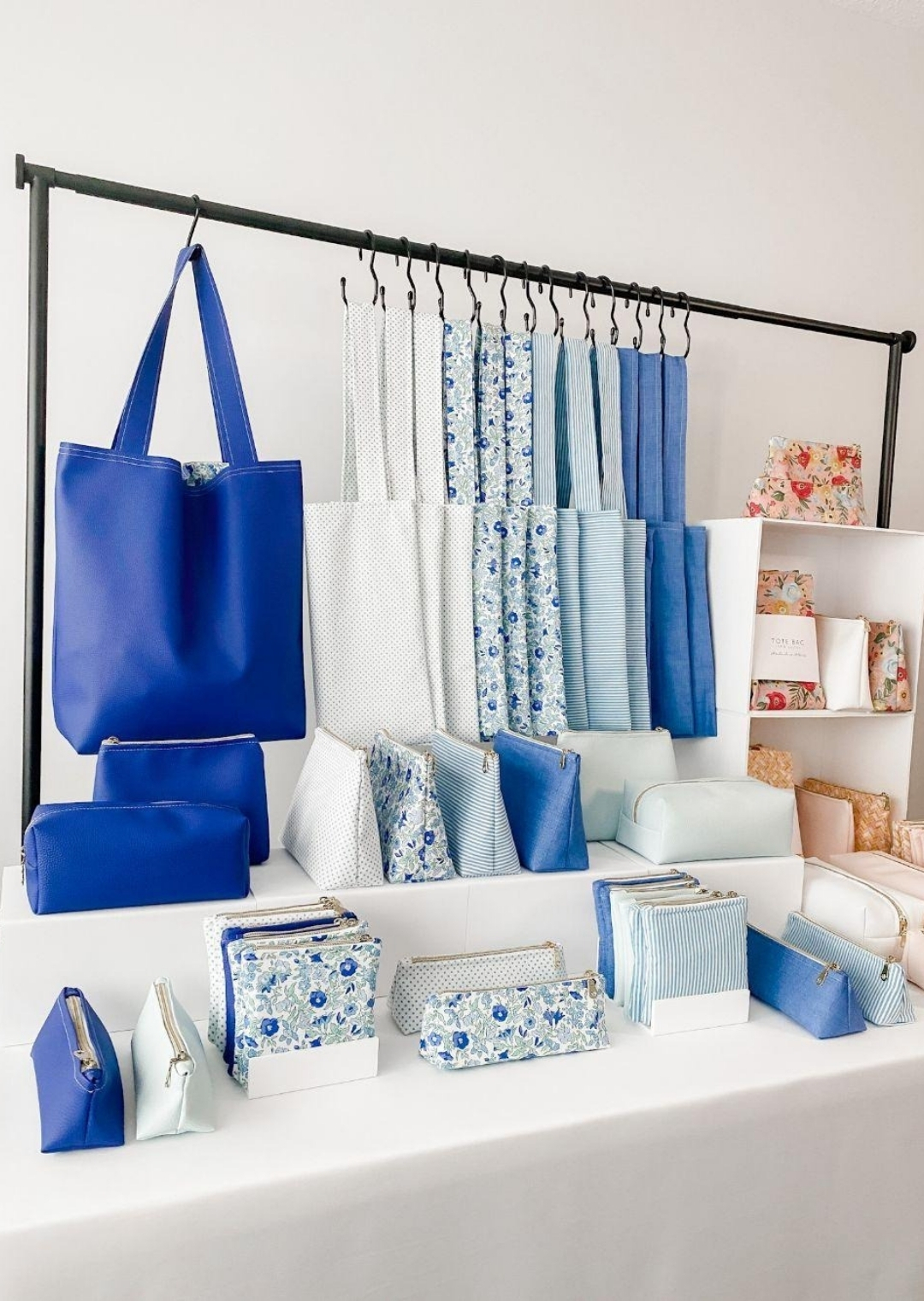 Οργανωμένο display καταστήματος με μπλε τσάντες, νεσεσέρ και αξεσουάρ σε καθαρή χρωματική ομαδοποίηση για visual merchandising.